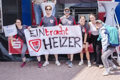 Gruppe von Menschen hält bei einer Veranstaltung ein großes Banner mit der Aufschrift „EINtracht HEIZER“.