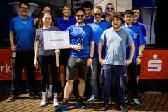 Gruppe junger Sportlerinnen und Sportler posiert mit einem Schild „Axtwerfen“ bei einer Veranstaltung.