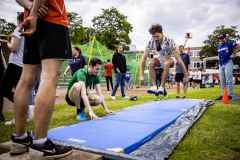 Junge Männer trainieren auf einer Sportplatz-Matte einen Weitsprung oder Salto.